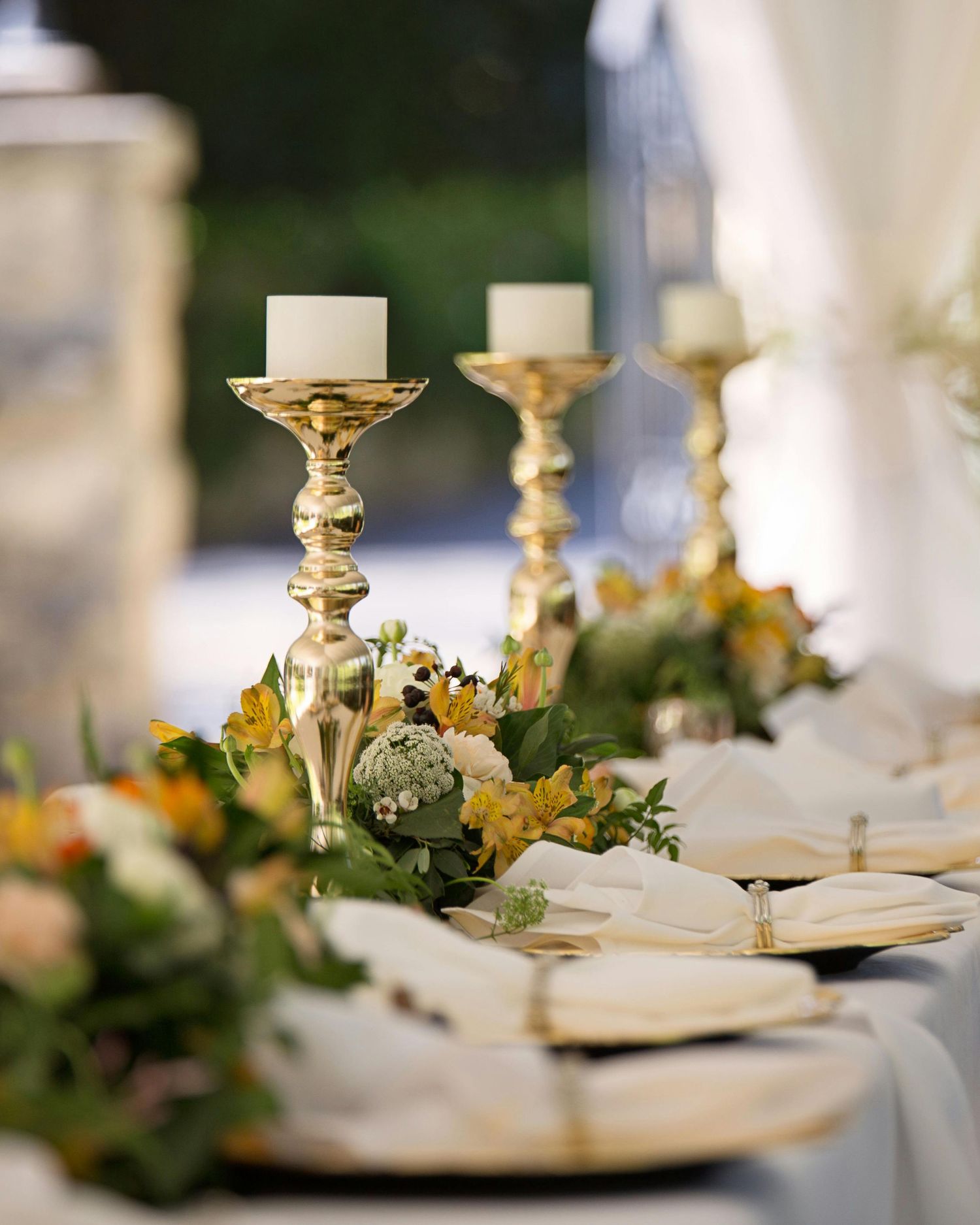 Elegant gold candelabra and floral arrangements adorn a formal dining table with white place settings.