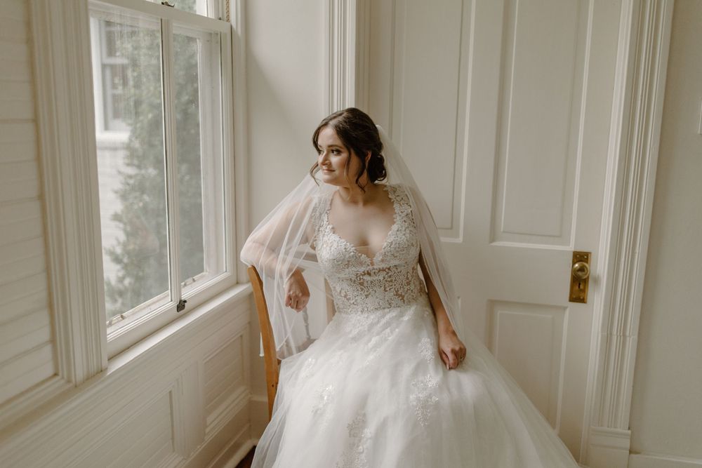 Artistic bridal portrait showcasing delicate lace bodice and tulle skirt in warm window light.