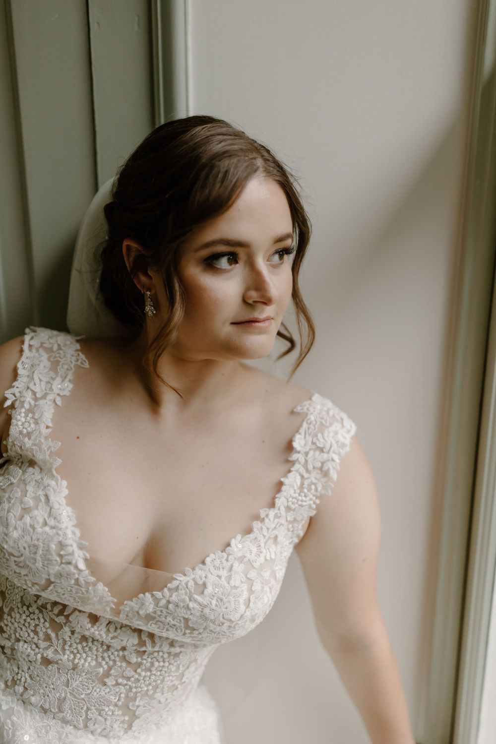 Soft natural window light illuminates a romantic bridal portrait with delicate lace details.