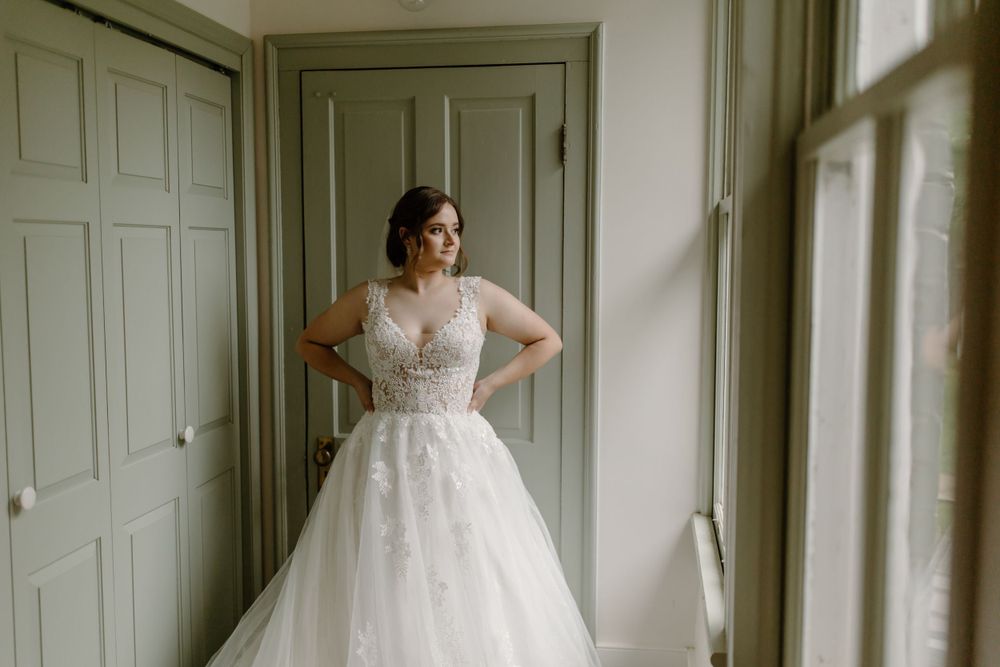An elegant bridal photo showcasing a classic ballgown silhouette against a sage green door.