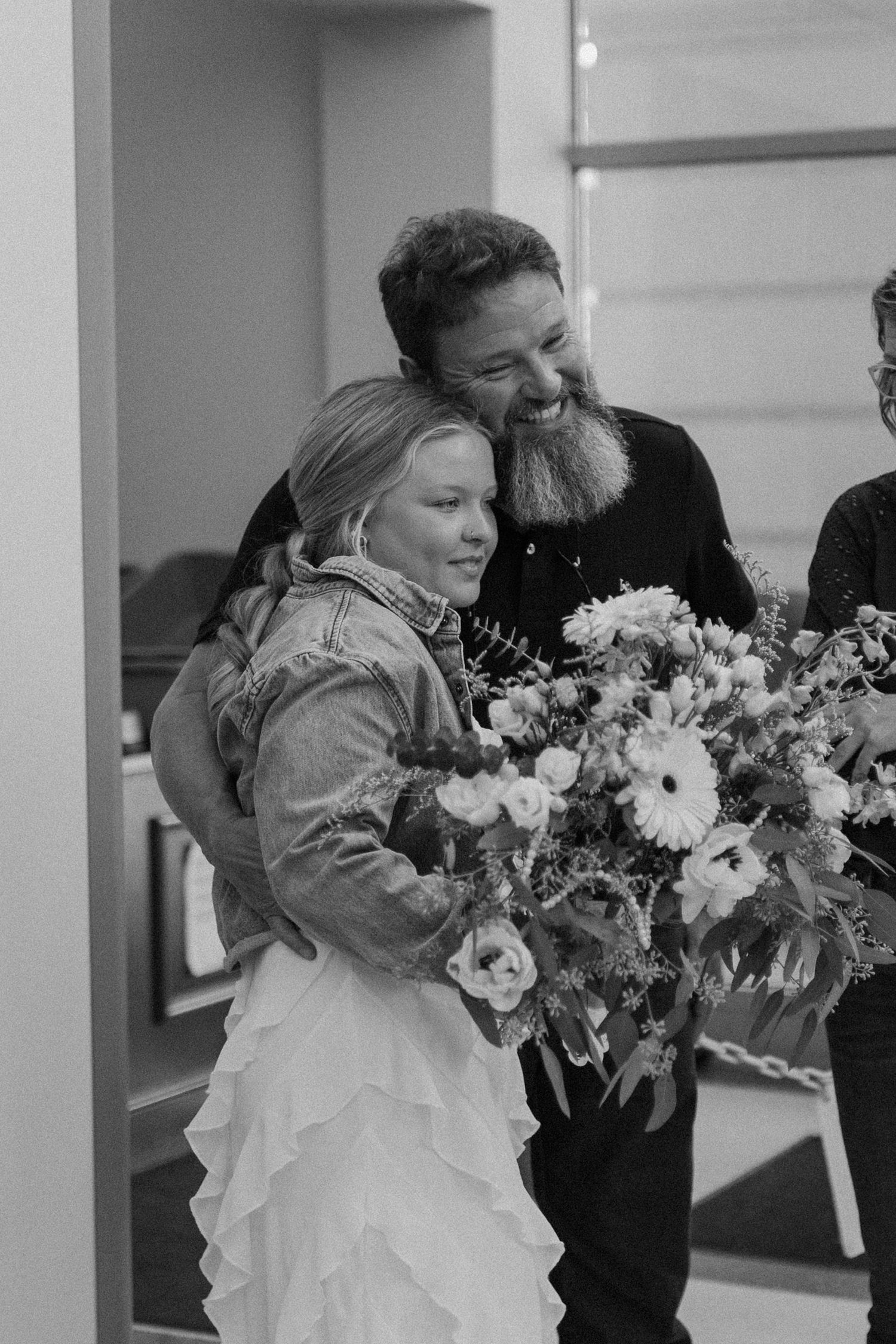 A heartwarming black and white photo showing people with a large floral bouquet in an indoor setting.
