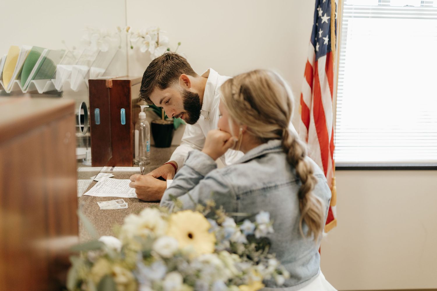 An intimate ceremony taking place in an office with flowers and an American flag.