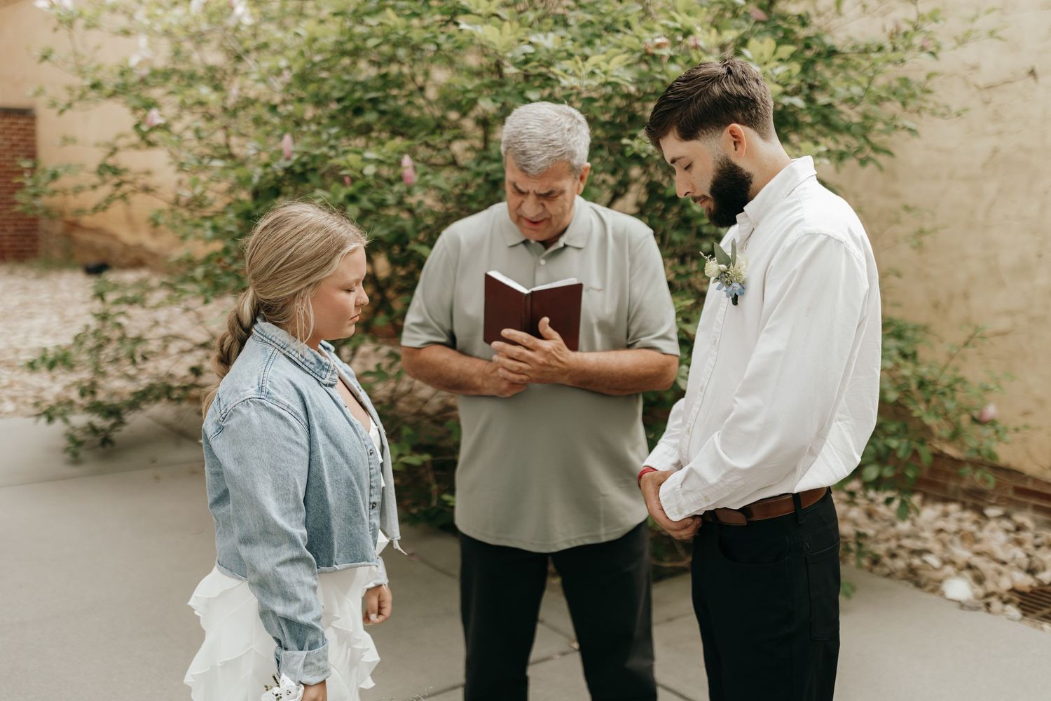 Three people stand together outdoors during what appears to be a small ceremony.