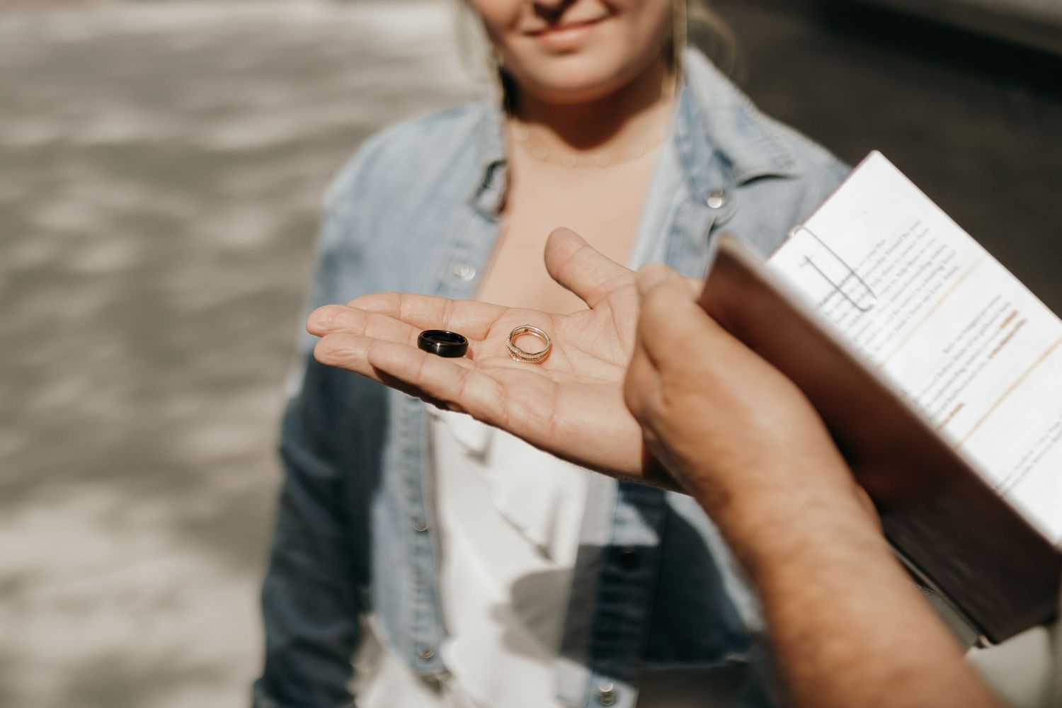 Hands holding wedding rings in bright sunlight.
