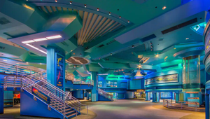 Modern aquarium interior with blue lighting, curved architecture and a grand staircase.