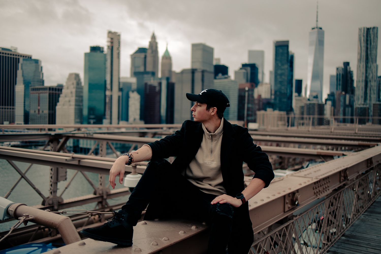 Cinematic portrait of a young man in black coat and cap overlooking city skyline, visionary South Florida photographer and visual artist.