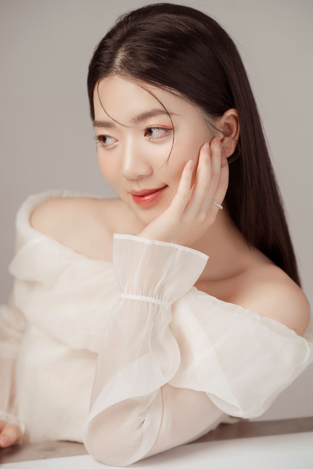 Minimalist beauty portrait with clean styling and white fashion details against neutral backdrop.