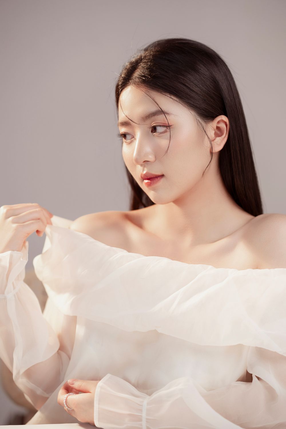Artistic portrait showcasing a delicate white chiffon blouse against a neutral gray background.