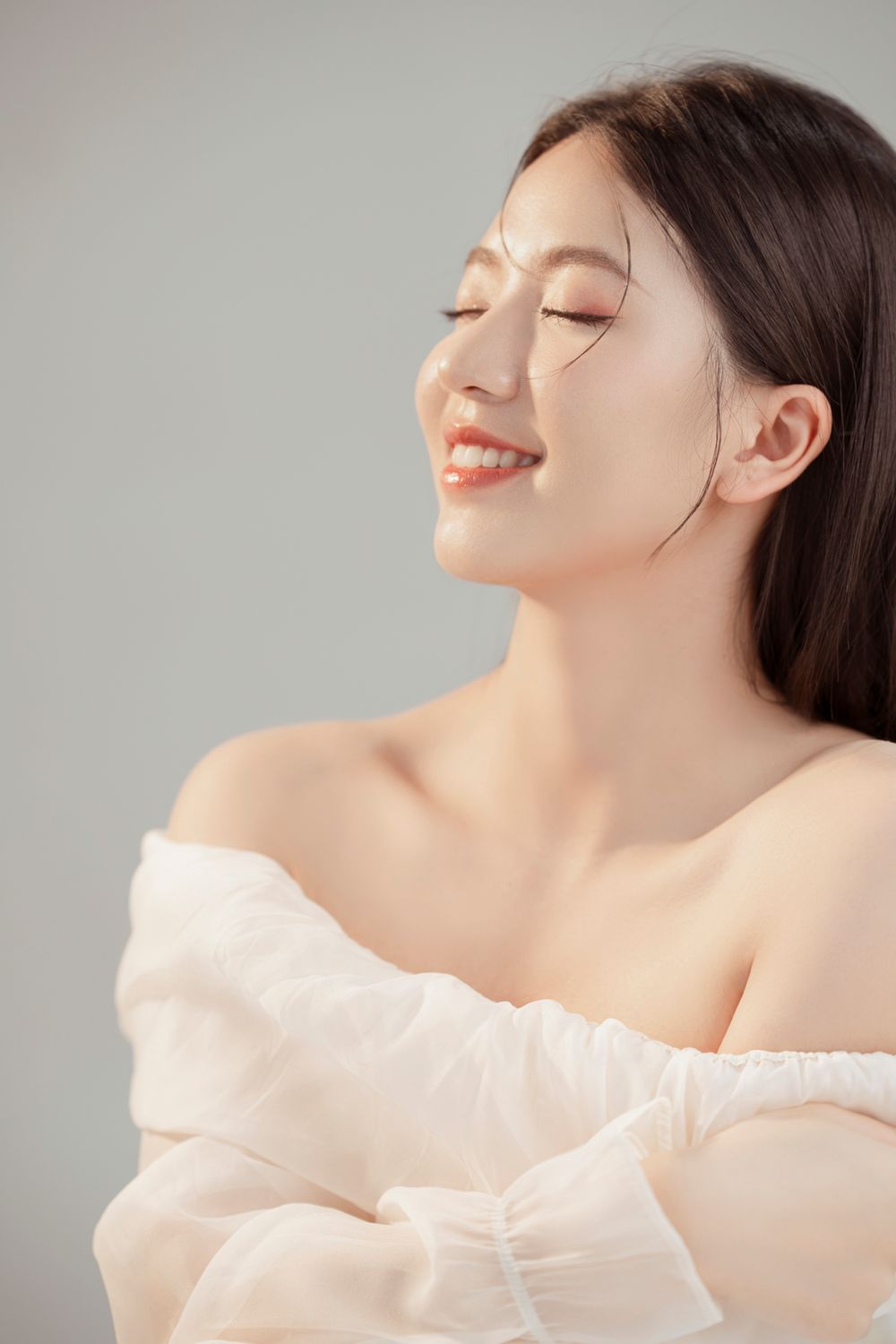 Serene profile portrait with closed eyes and soft white draped fabric.
