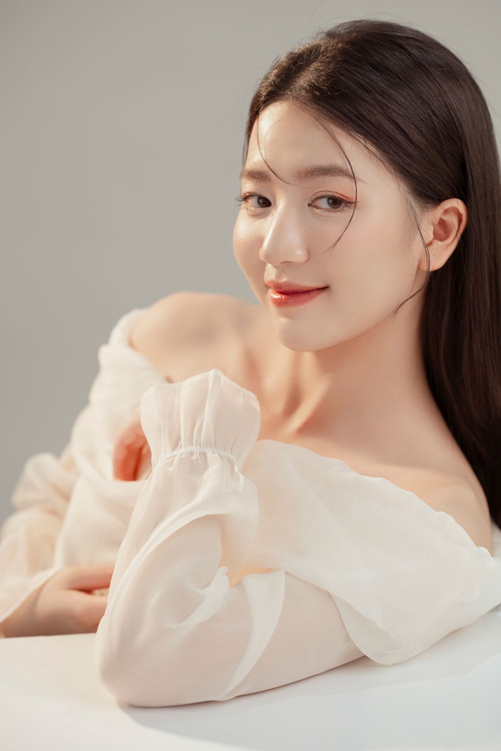 Elegant beauty portrait featuring off-shoulder white fabric and natural makeup.
