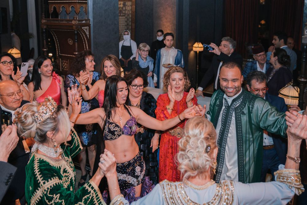 People dancing and celebrating at a lively indoor party with festive decorations and dim lighting.