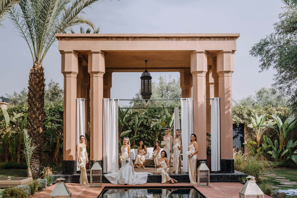 An elegant outdoor wedding ceremony setup with stone pillars and palm trees framing a luxurious venue.