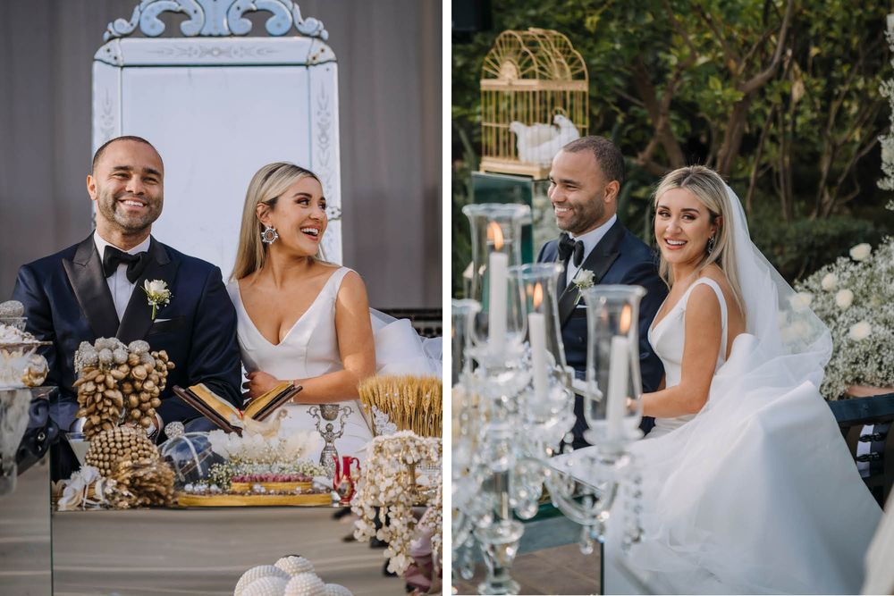 Wedding couple celebrates at a elegantly decorated reception with white floral arrangements and candles on table.