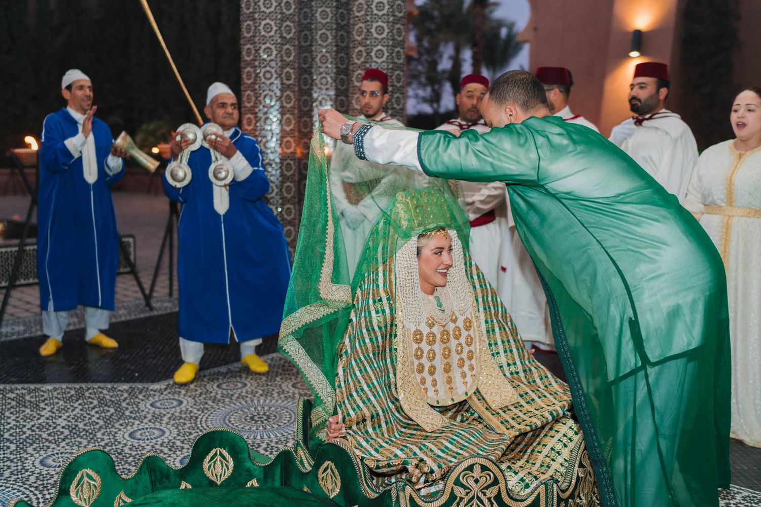 Traditional Moroccan wedding celebration with performers in blue and green ceremonial attire during a cultural ceremony.