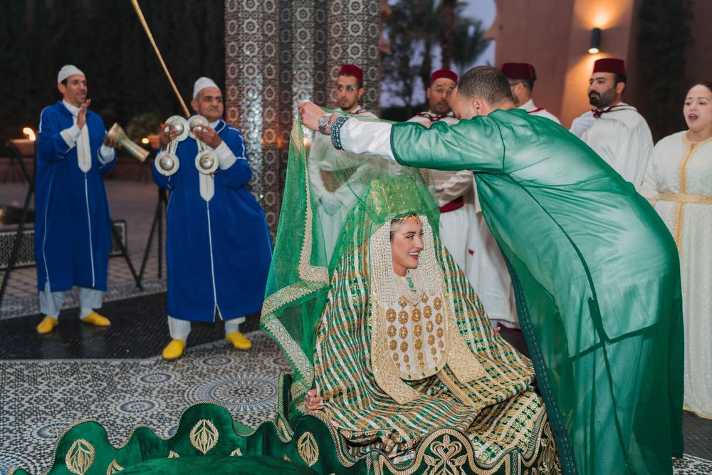 Traditional Moroccan wedding celebration with performers in blue and green ceremonial attire during a cultural ceremony.
