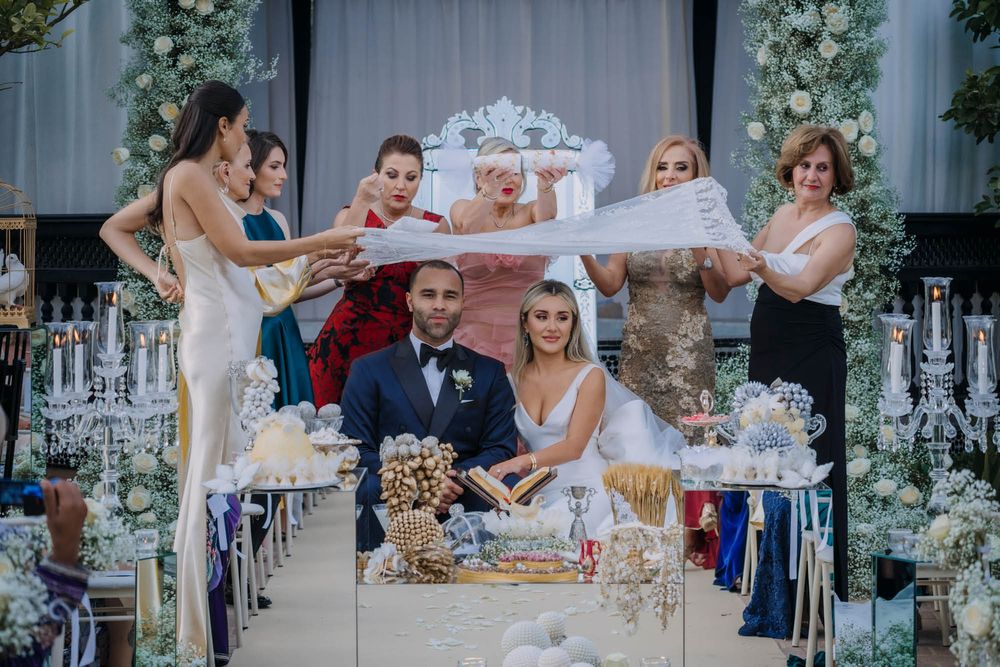 Wedding party celebrates at an elegant reception with sparklers and decorative table settings amid floral arrangements.