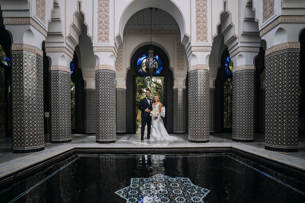 Elegant wedding ceremony setting at a Moroccan-style courtyard with ornate pillars and reflecting pool.