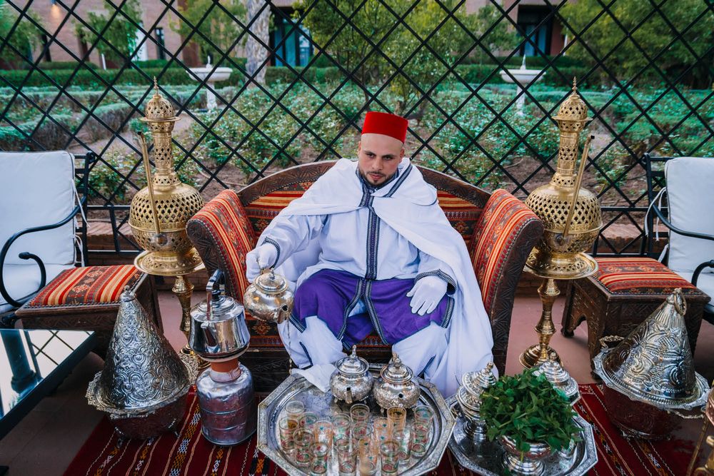 A traditional Moroccan tea setting on an outdoor terrace with ornate silver teapots and decorative brass lamps.