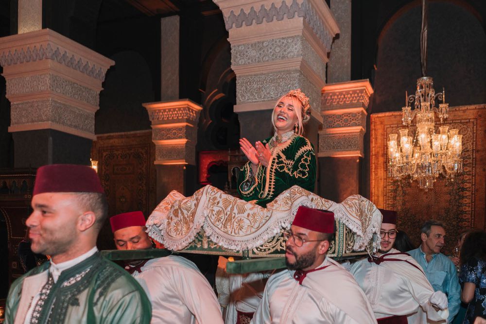 A performer in traditional costume is lifted during an entertainment performance in an ornate venue.