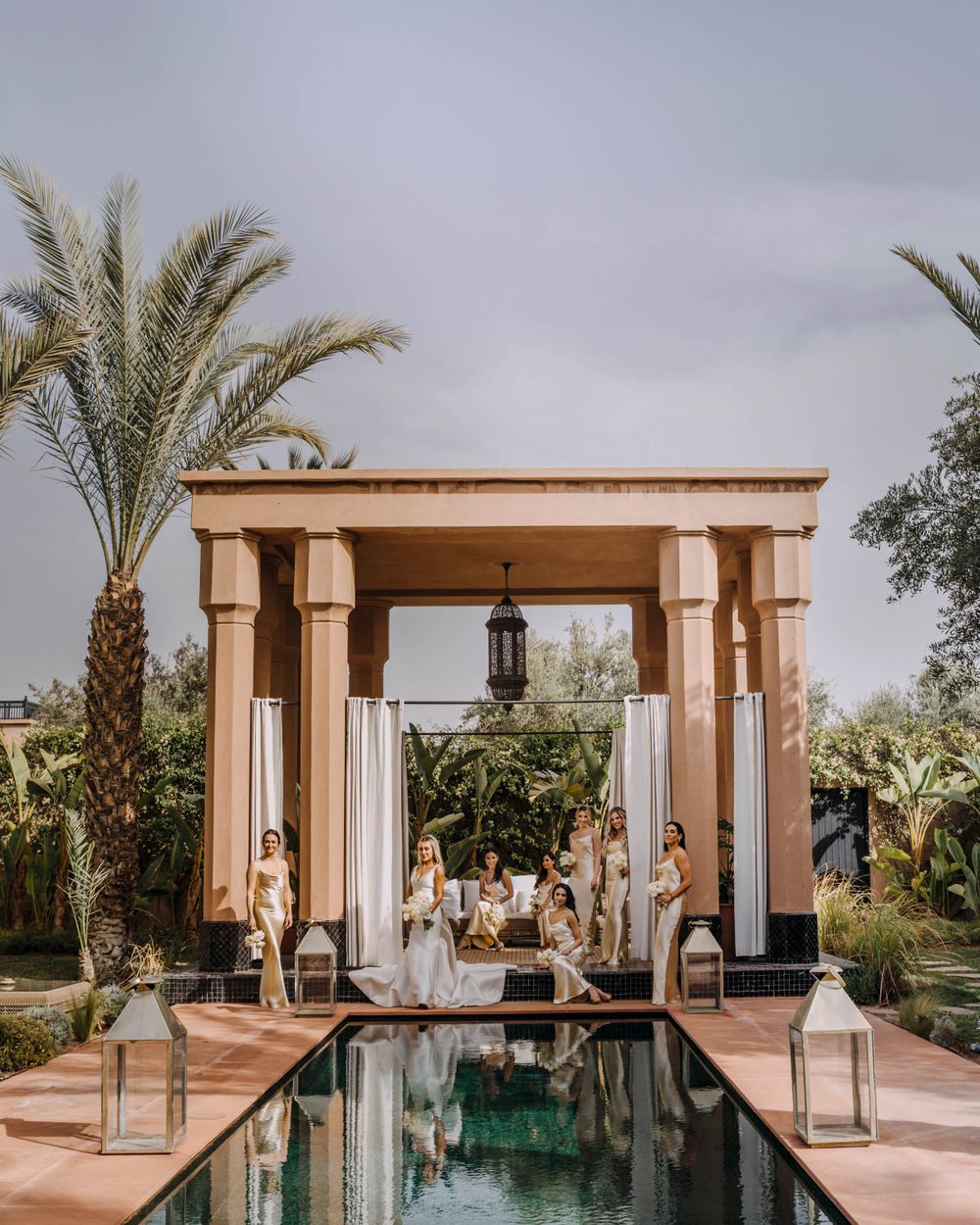 Elegant poolside gazebo with white columns and curtains surrounded by palm trees at a luxury resort in Morocco.