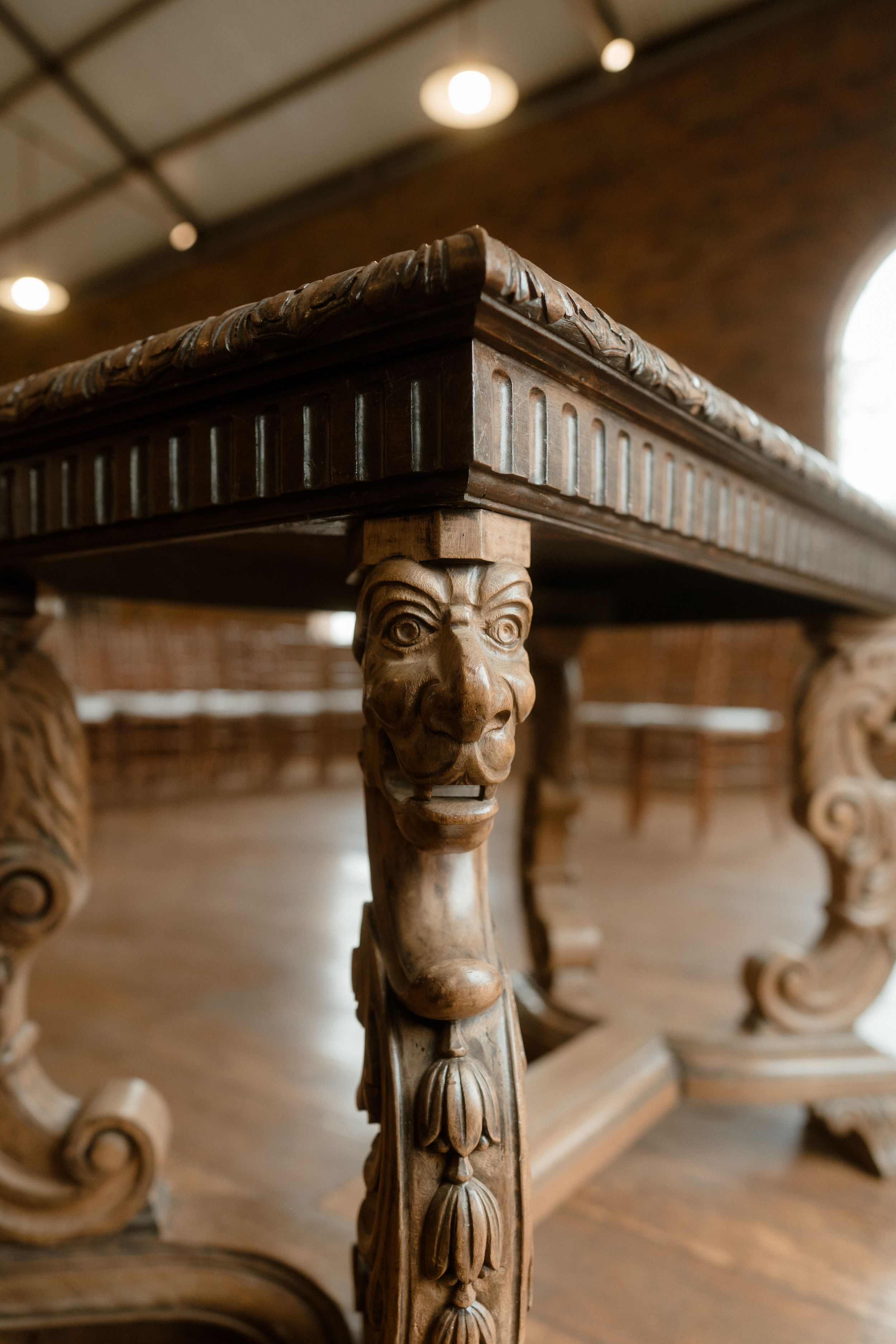 Ornate carved wooden face detail on antique church furniture.