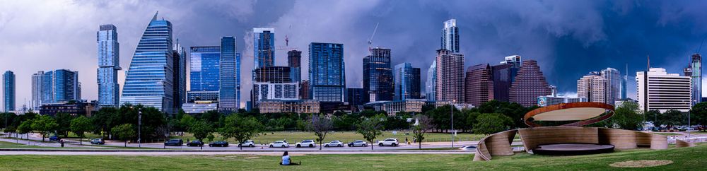 Panoramic view of Houston skyline against stormy sky with park in foreground.