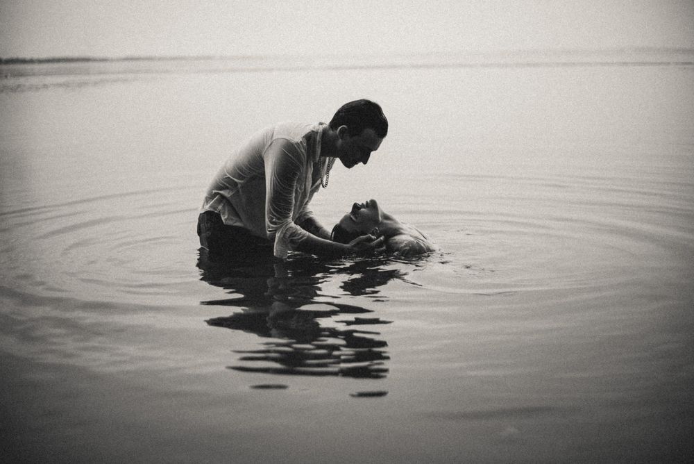 Moody black and white silhouettes of figures in water creating a minimalist scene.