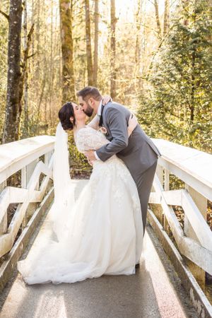 A couple do a dip kiss during golden hour on a small white bridge in Langley, BC.