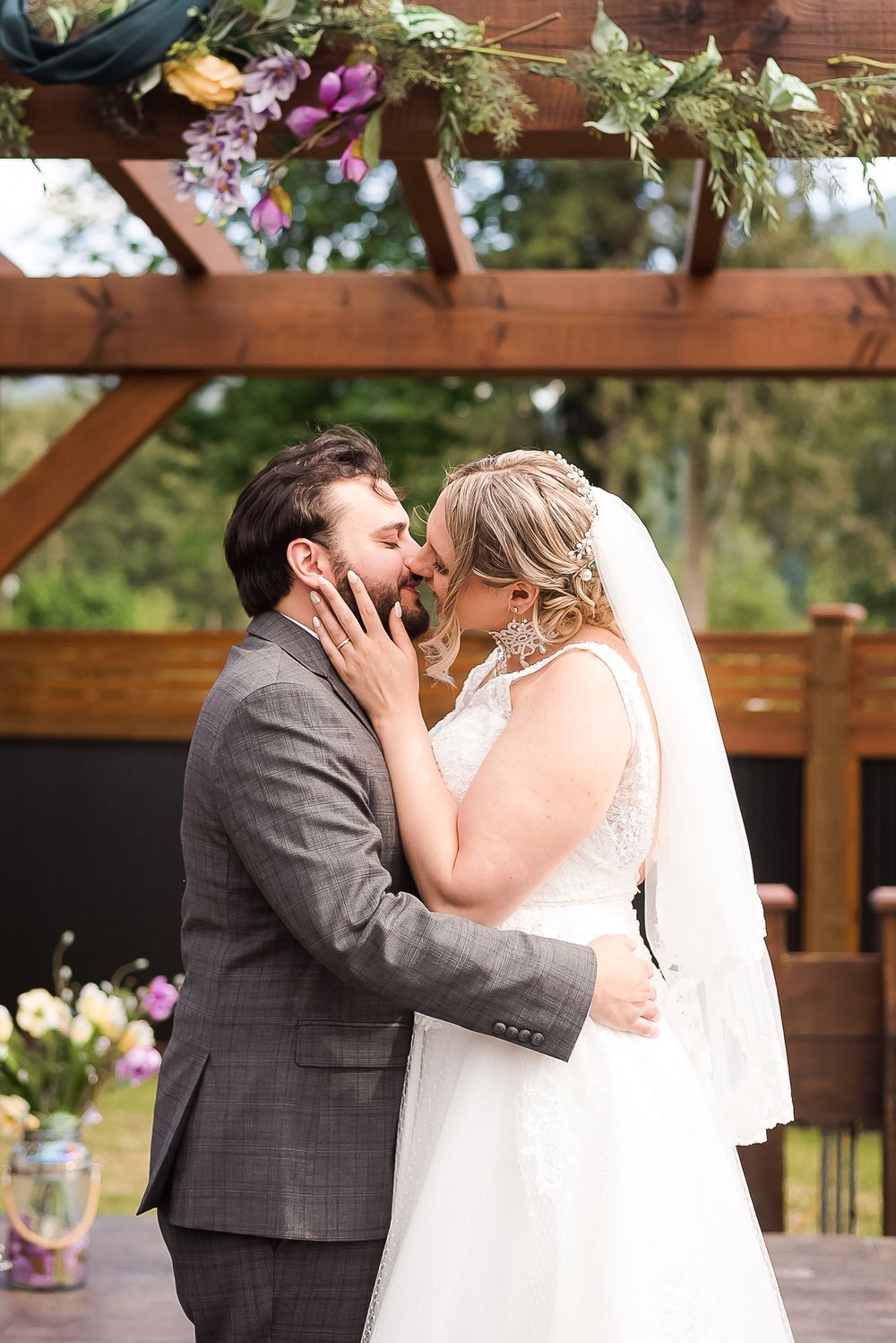 A couple share a sweet first kiss during their wedding ceremony. Photo taken at Bridlewoods Venue in Chilliwack, BC