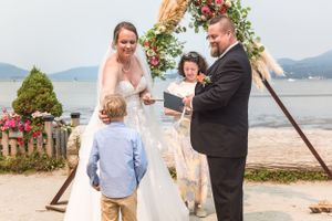 During a beach wedding ceremony, the couple's children bring the rings up to their mom and dad. Ceremony at Spanish Banks Beach, Vancouver.