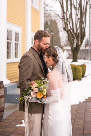 A vintage 1920's inspired wedding on a snowy February afternoon. The groom gently kisses the bride's head. Fort Langley, BC.