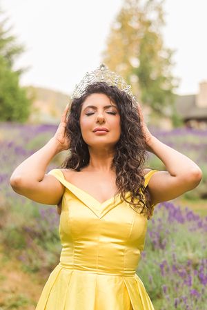 An Indian beauty queen dressed in a yellow gown, poses with her crown in a field of lavender. Steelhead Lavender Farm, Mission, BC.
