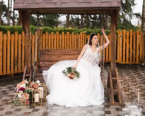 On a rainy west coast afternoon, a bride poses on a wooden swing surrounded by autumn colours and flowers. Wedding venue in Pitt Meadows, BC