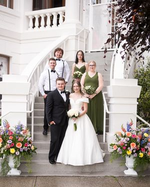 A stylish wedding party, including the bride and groom, pose together on a grand staircase in downtown Chilliwack, BC, (Chilliwack museum).