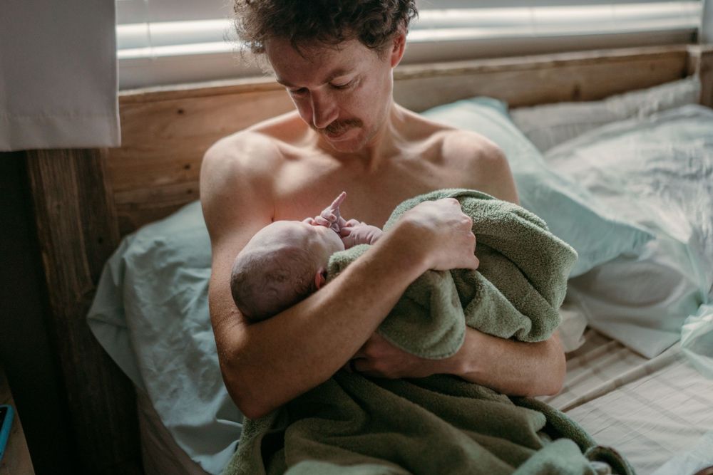 Tender moment between parent and newborn wrapped in soft towel.