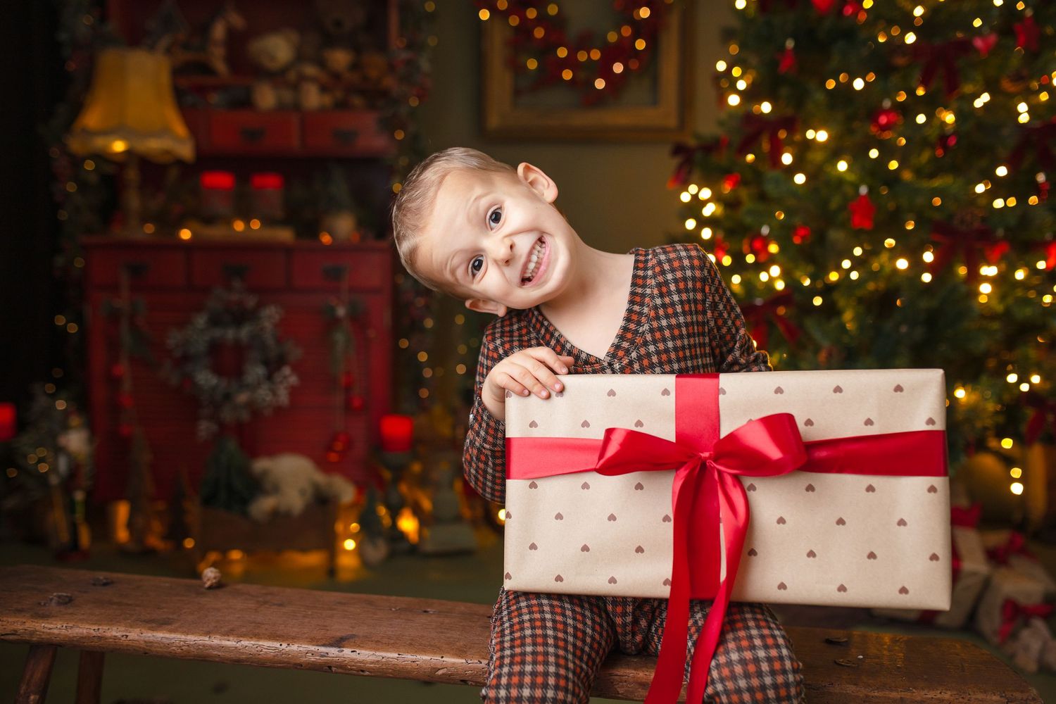 Small child in vintage dress holding white bunny decorations in festive holiday setting.