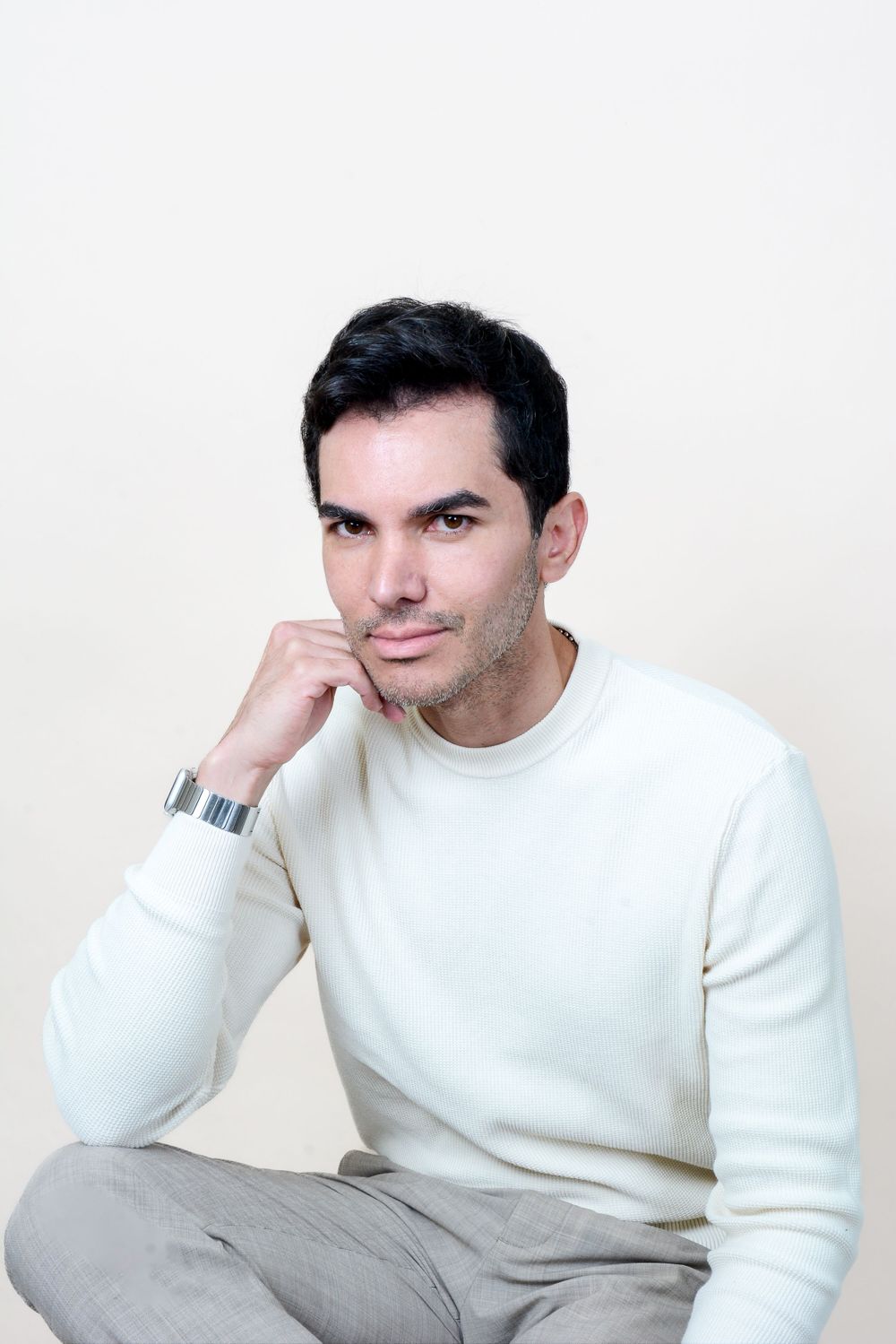 Portrait series of person in cream sweater and grey pants posing thoughtfully.