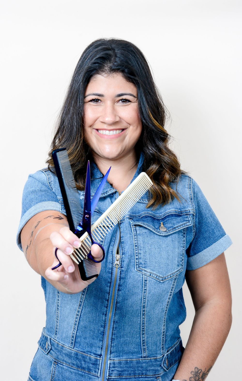 Playful portrait series of person in denim vest holding hair styling tools.