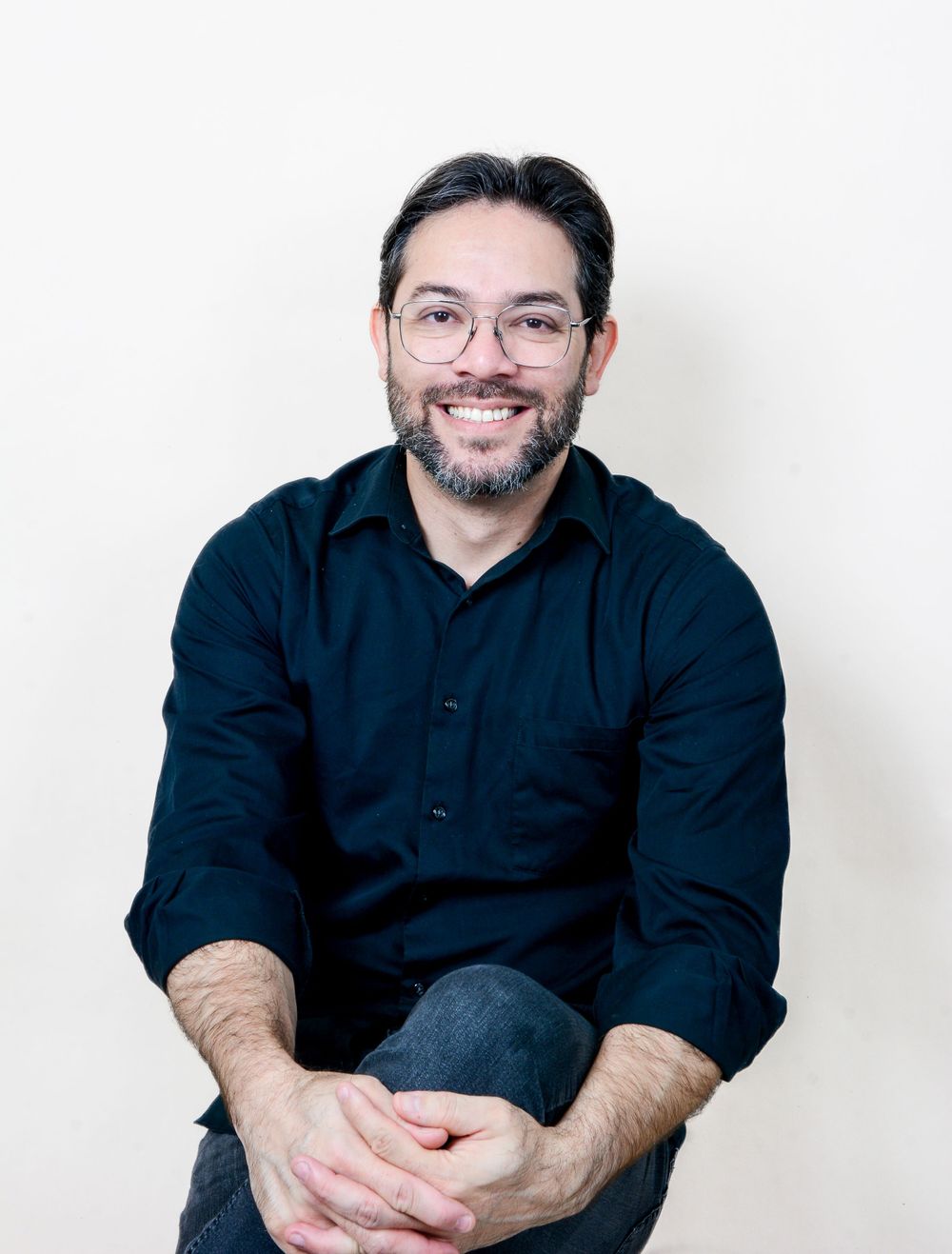Professional headshots showing person in black shirt against white background smiling warmly.