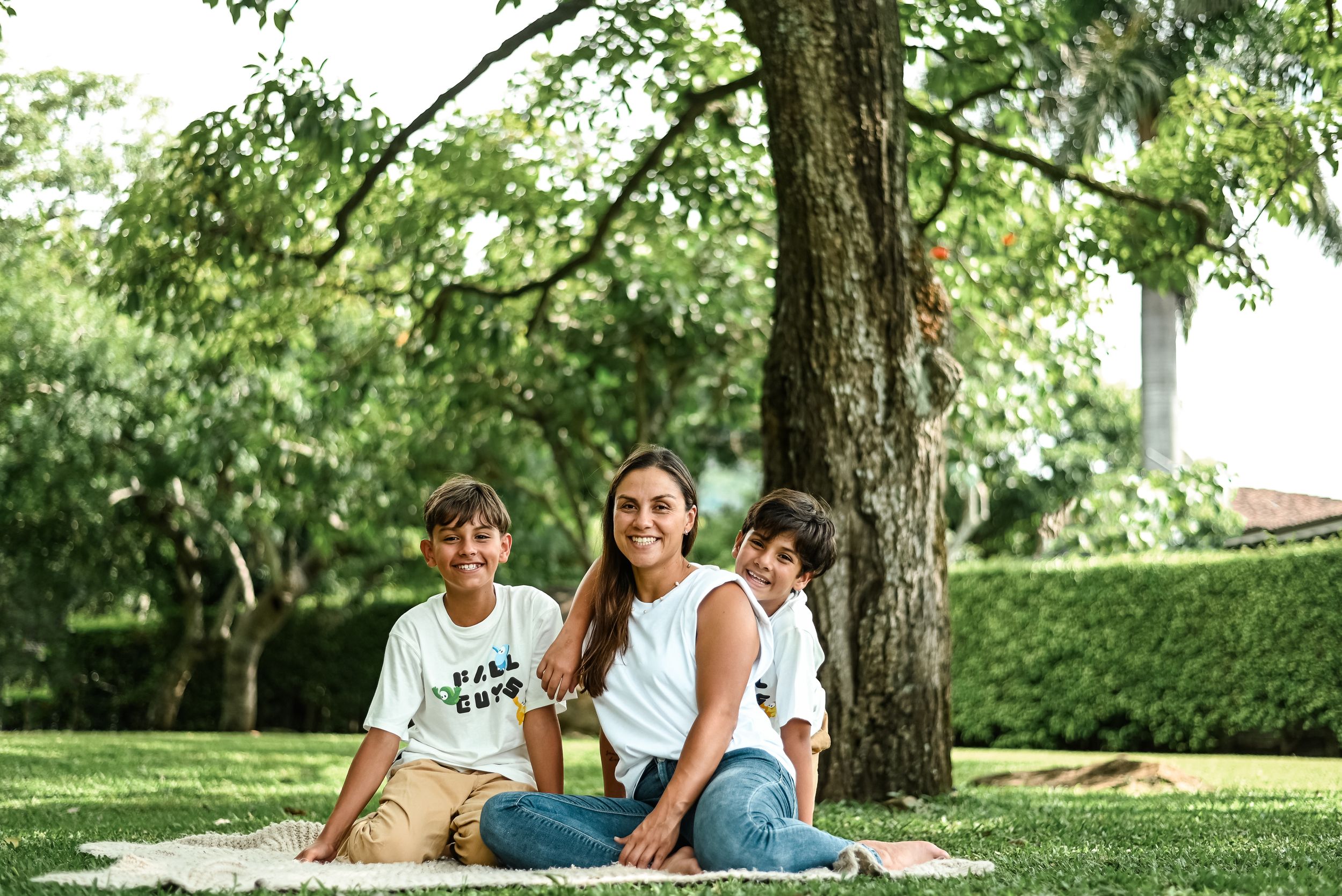 Family enjoying a relaxing summer day together under a shady tree in a lush green park.