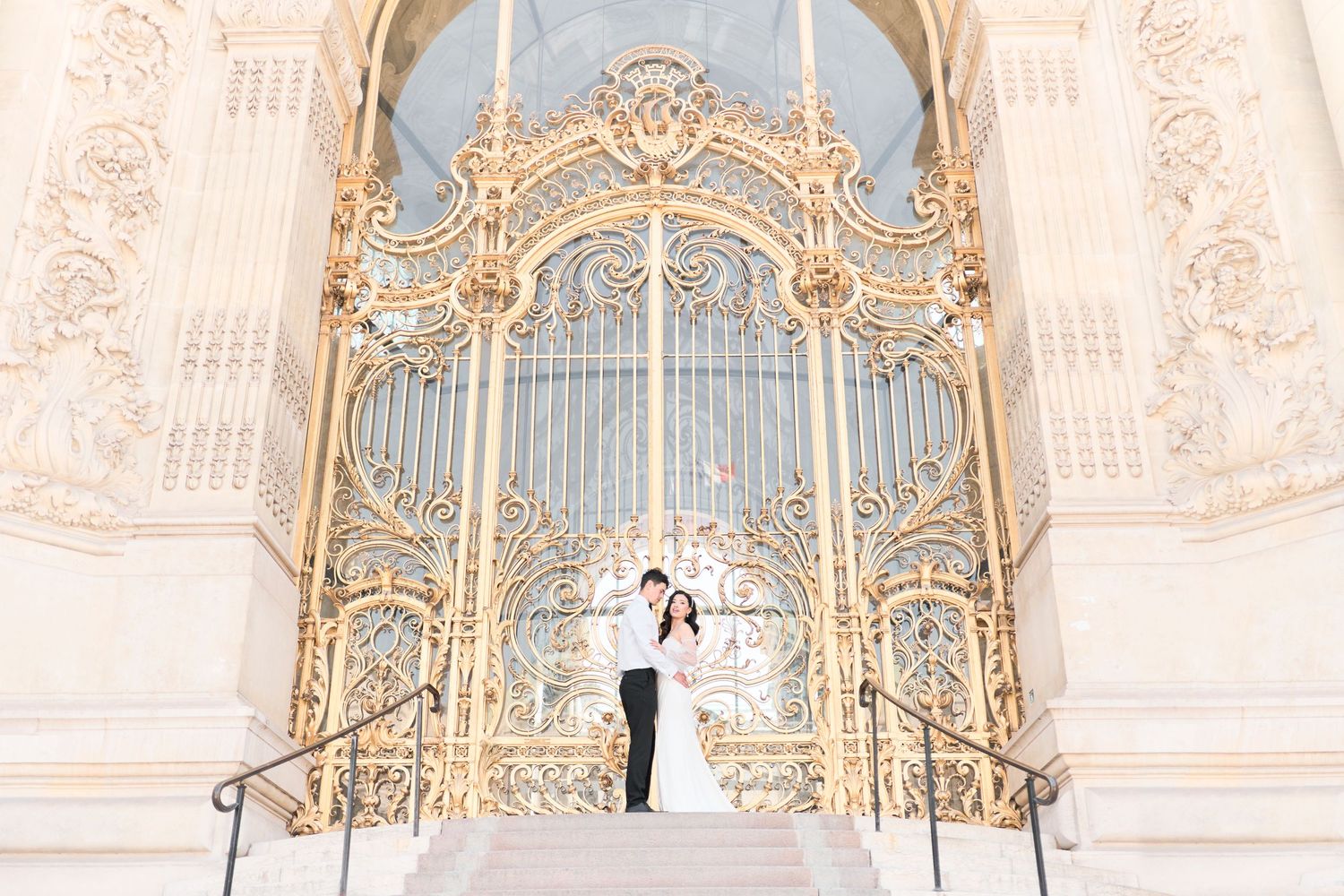 Paris wedding photographer captures a romantic photo of a bride and group outside the stunning Petit Palais golden gates in Paris, France