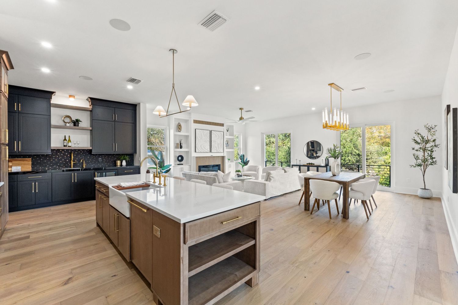 Luxurious open concept kitchen with dark cabinets and white countertops extending into living space.