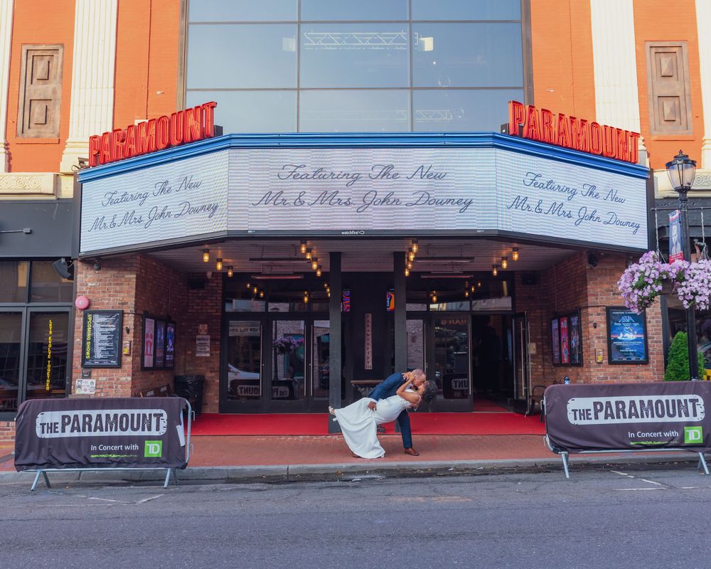 Art deco marquee and entrance of the historic Paramount Theatre with red carpet and decorative neon signage against blue sky.