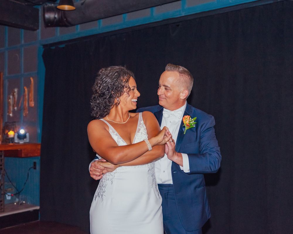 A couple shares an intimate dance moment at their wedding reception in a dimly lit venue.