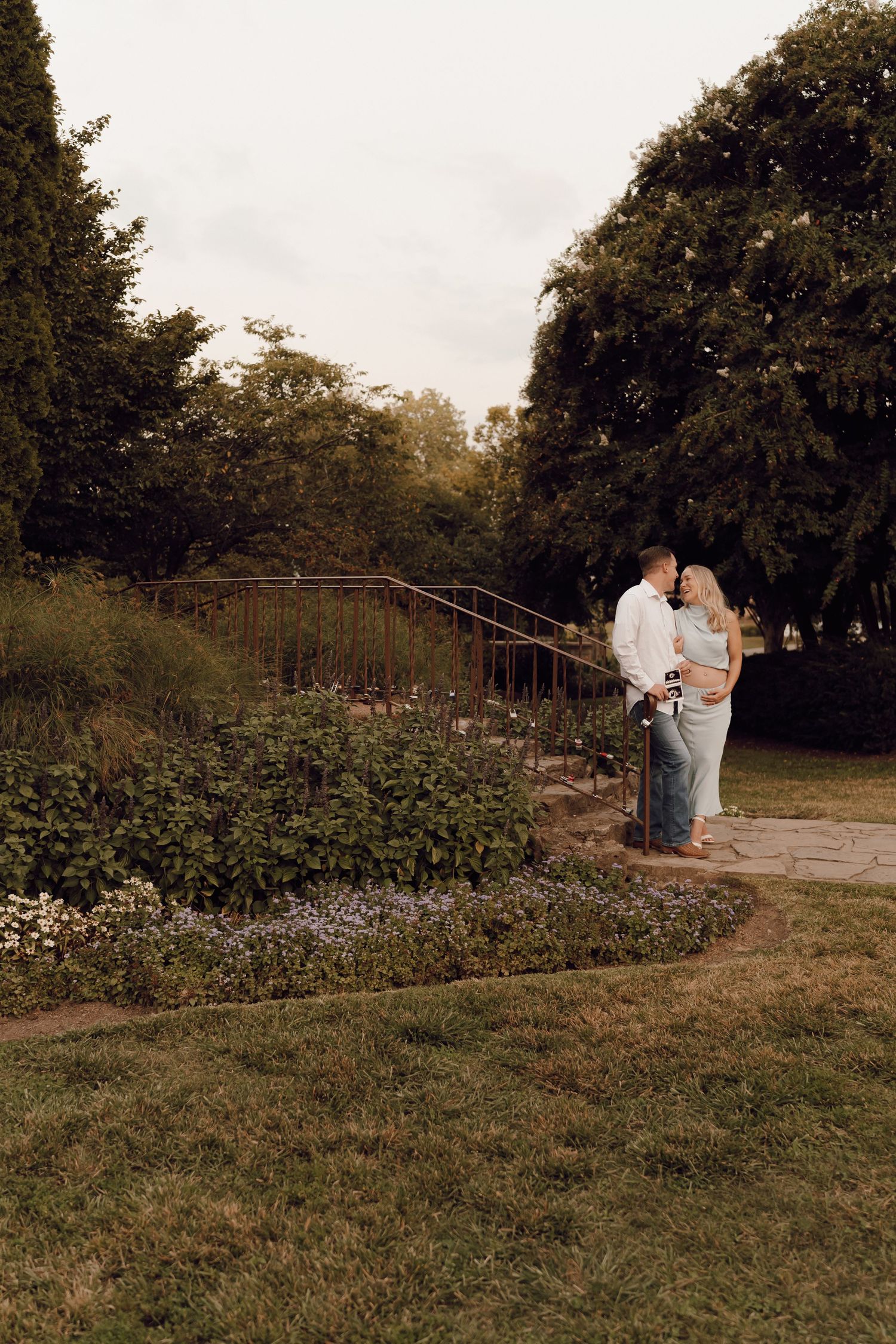 Elegant maternity portrait of a woman with a glowing smile, standing in a scenic outdoor location.