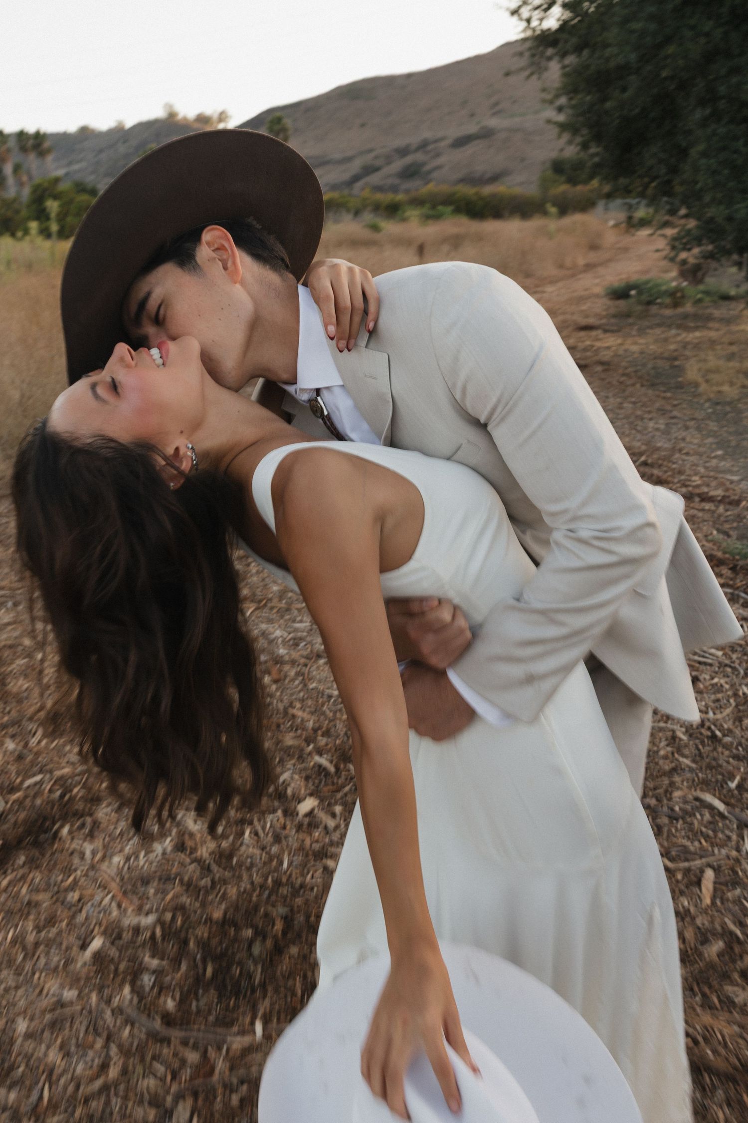 A romantic wedding moment captured with the couple sharing an intimate embrace against a dark background with warm lighting.