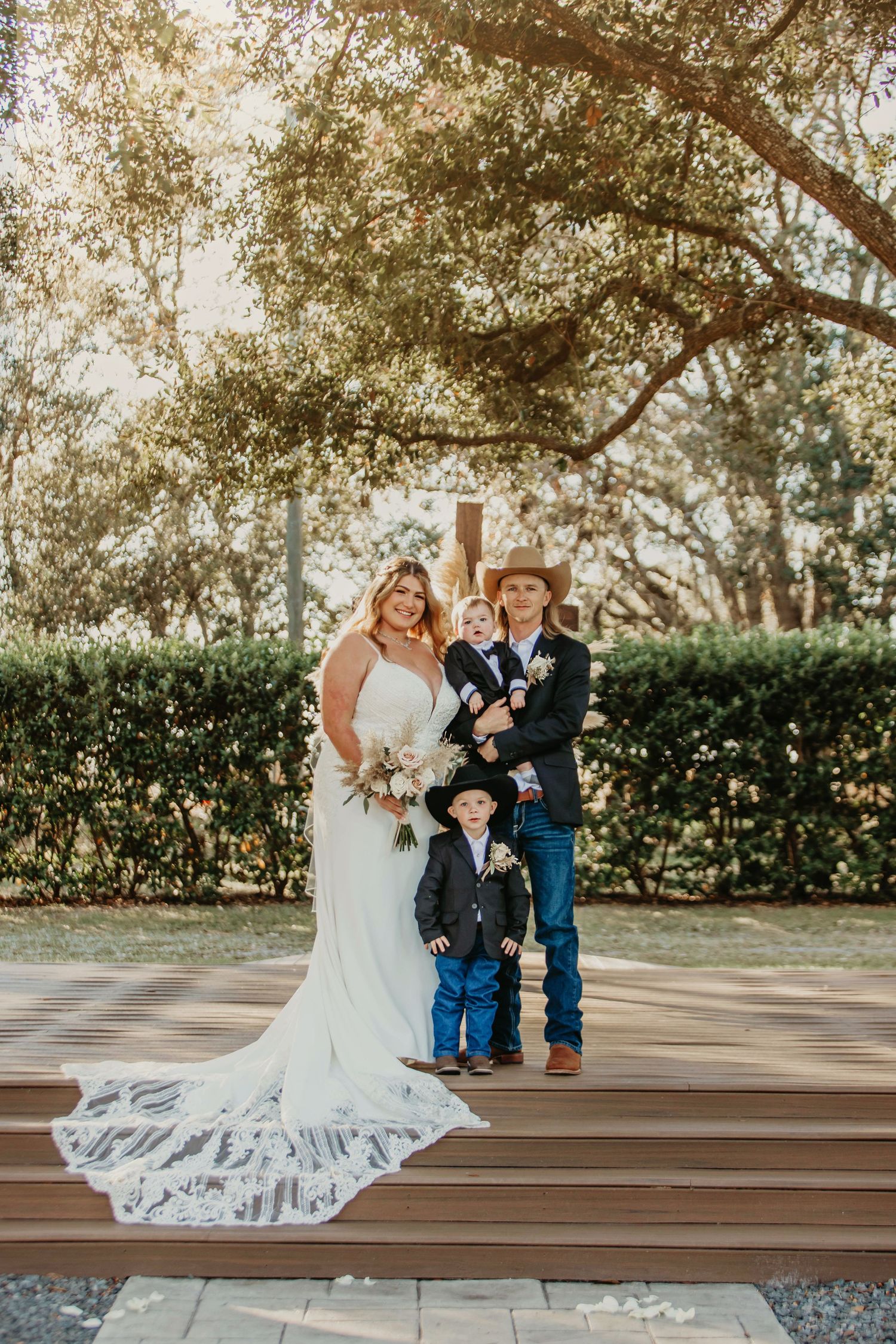 Wedding portrait on wooden deck with trees and greenery in background.