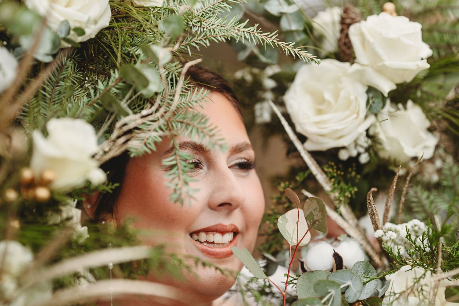 Ethereal portrait through delicate white roses and ferns creating a dreamy natural frame.