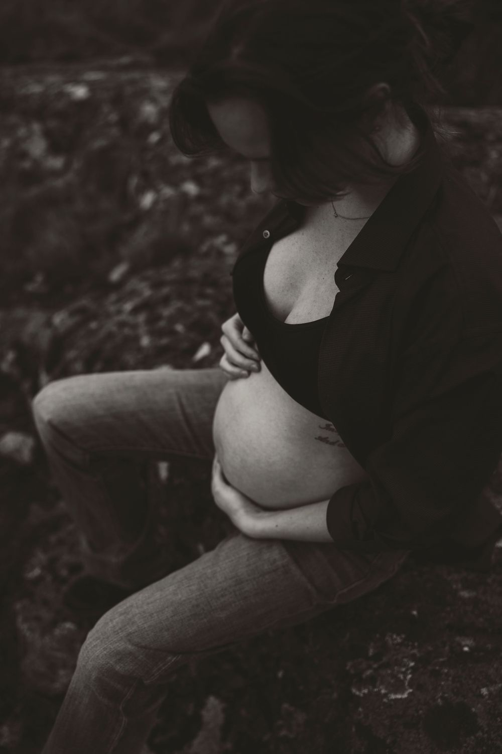 Intimate black and white maternity portrait in natural outdoor setting.
