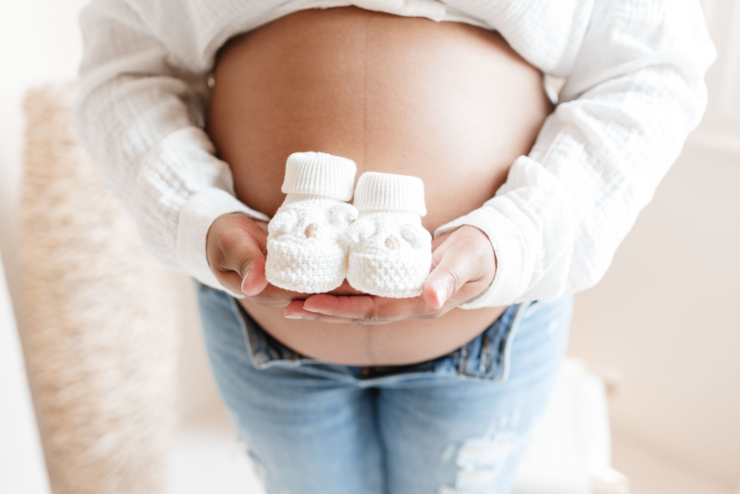 Mom holding baby shoes for maternity photoshoot in toronto studio